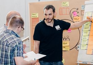 Peter Fischbach mit Teilnehmern im Scrum Workshop an einem Flipp Chart